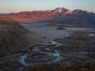 Güneş battıktan sonra dağlarda bir nehir kıvrımında dünya dışı bir manzara..