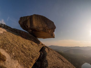 Uçurumun üzerinde büyük granit kayalar asılı. Gün batımında kayalara yaslan. Batı Sayan 'da bulunan doğal jeolojik fenomen. 