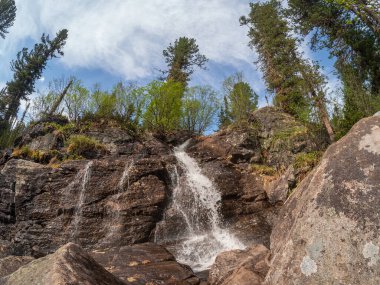 Waterfall on the mountain. Beautiful summer mountain waterfall. Nature background of turbulent falling water stream on wet rocks. Western Sayans. clipart