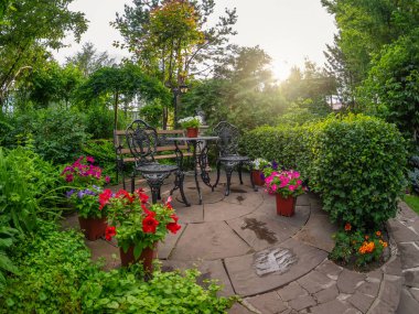 Siyah işlemeli demir masa ve bahçenin arkasındaki sandalye. Yaz bahçesi avlusu. Yaz parkının güzel manzarası..