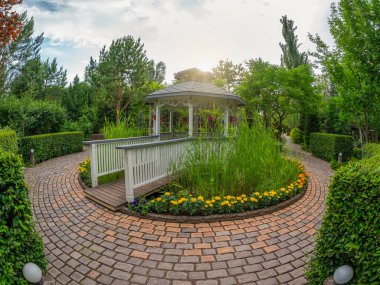 Yaz bahçesi avlusu. Yaz parkının güzel peyzajı. Bahçenin dibinde açık bir çardak var. Açık Bahçe Dekorasyonu. Abakan. 