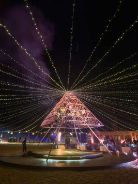 Dubai, BAE - 29 Mayıs 2024: Çöl ışıkları. Karanlıkta piramit ışığı. Dubai 'de göbek dansı ve ateş dansı eğlence şovu için eşsiz bir çöl turizmi yeri. Dikey görünüm.