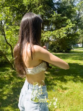 Uzun siyah saçlı, güzel ve çekici bir kadının yaz parkında yoga yapması. Aktif bir yaşam tarzı. Dikey görünüm.