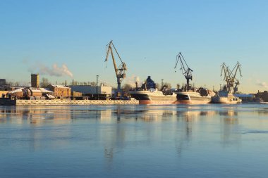 Gemi ve liman vinçleri St. Petersburg Neva nehrinde demirli. Kargo konteynır deposu, konteyner gemisi terminali, tersane. İş ve ticaret, lojistik. Kış sanayi sahnesi.