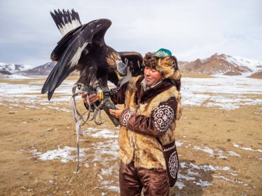 Ulgii, Moğolistan - Ekim 01, 2023: Bir yarışmada altın kartal avlayan deneyimli bir erkek avcının portresi. Kartal avcıları Moğolistan 'da altın kartallarla eğitip avlanan insanlardır..