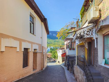 Gurzuf, Kırım - 17 Ekim 2024: Gurzuf, şehrin eski gölge caddesi. Gurzuf sokaklarında yürüyen turistler. Gerçek bir şehir hayatı. Güzel bir sonbahar günü.