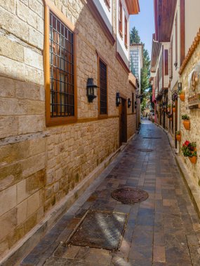 Antalya. Türkiye, 22 Şubat 2025, akşamları butik mağazaları olan eski kasabada gölgeler dar sokak manzarası. Türkiye 'de popüler bir turizm merkezi. Kış zamanı, turist yok. Dikey görünüm