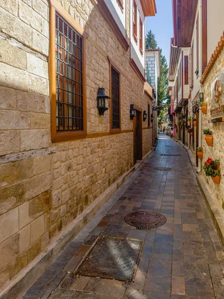 Antalya. Türkiye, 22 Şubat 2025, akşamları butik mağazaları olan eski kasabada gölgeler dar sokak manzarası. Türkiye 'de popüler bir turizm merkezi. Kış zamanı, turist yok. Dikey görünüm