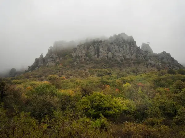 Bulutlu bir siste uzak uçurumlar. Kırım Yarımadası 'ndaki Hayalet Vadisi. Sis içindeki kayalar.
