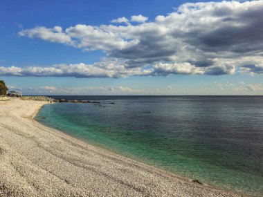 Çakıl taşı plajı ve beyaz bulutlu mavi deniz. Güneşli havada doğal minimalist deniz manzarası. Kırım Yarımadası Kıyısı.