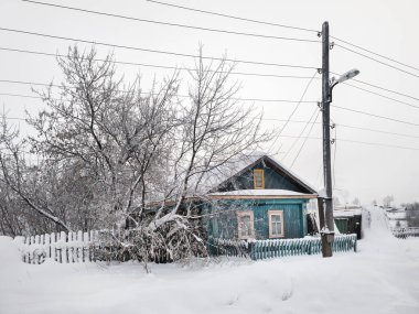 Karlı bir kışta Rus kulübesi. Kış köyü, kar yağışı, Kuzey 'in sert doğası, şiddetli don, minimalist kış görüntüsü. Perma bölgesi