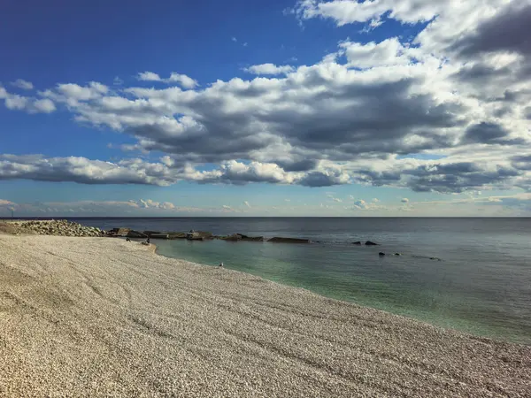Kırım Yarımadası kıyısında. Çakıl taşı plajı ve beyaz bulutlu mavi deniz. Güneşli havada doğal minimalist deniz manzarası.