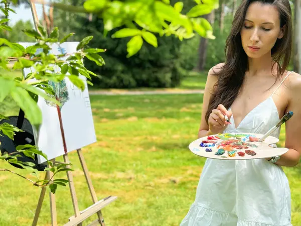 Sanat terapisi. Bahçesinde yaratıcı düşünceli, narin, genç bir kız vardı. Genç, güzel bir sanatçı bir yaz parkında yalın bir havada resim yapıyor..