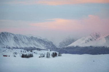 Yükselen güneş, Altai Cumhuriyeti 'ndeki Severo-Chuisky Dağı' nın pembe tepelerini boyadı. Yumuşak mor ışık, sabahın erken saatlerinde dağların tepelerinde süzülür..