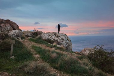 Gün batımında dağdaki yürüyüşçü. Kırım 'dan güzel bir gün batımı manzarası ve bir kayanın üzerinde duran bir adam.