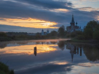 Dunilovo ayna nehri olan antik bir köy. Duyuru Manastırı, İvanovo Bölgesi, Geniş Nehir, Ufuk, Bulutlar suya yansıyor. Sabah manzarası, nehirde gün doğumu. Altın Yüzük
