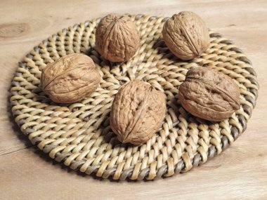 Örülmüş, yuvarlak bir peçeteye sarılı ceviz kabuğu ahşap bir masanın üzerinde yatıyor. Kapat..