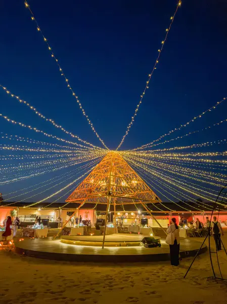 Dubai, BAE - 29 Mayıs 2024: Çöl ışıkları. Karanlıkta piramit ışığı. Dubai 'de göbek dansı ve ateş dansı eğlence şovu için eşsiz bir çöl turizmi yeri. Dikey görünüm.