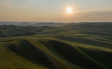 Yumuşak odaklanma. Rusya 'nın Orenburg bölgesindeki Dolgiye Dağları. Manzaranın havadan çekilmiş fotoğrafı. Güneşli bir sabahta tepelik bir arazi. Dağlardaki tarlalar. Ural dağlarının başlangıcı.