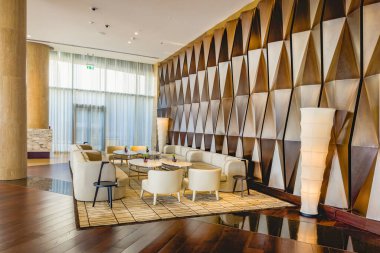 Abu Dabi, BAE - 31 Mayıs 2024: otelin lüks iç kesimi. Yumuşak deri koltuklar, yuvarlak masalar, odanın ortasında parlak renkli rahat sandalyeler..