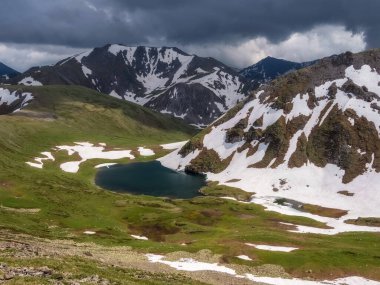 Yeşil çimenli tepeler ve karlı dağ sıralarına bakan kayalar arasında güzel, saf bir göl. Alp gölü ve karlı dağ vadisi olan manzaralı bir yer. Dağlık bölgelerdeki dağ gölü.