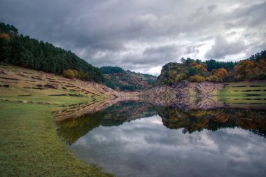 Portomarin yakınlarındaki Mino nehrinin kanyonu, Lugo Galicia Ribeira Sacra 'daki Portomarin nehrinin sakin sularına yansımaktadır.