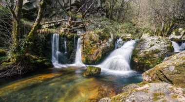 Three small waterfalls feed a pool of turquoise waters in the Courel Mountains Unesco Geopark in Lugo Galicia clipart