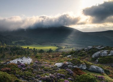 Bulutların arasından geçen ışık akıntıları Xistral Muras Lugo Galiçya 'daki dağlar arasındaki çayırı aydınlatıyor.