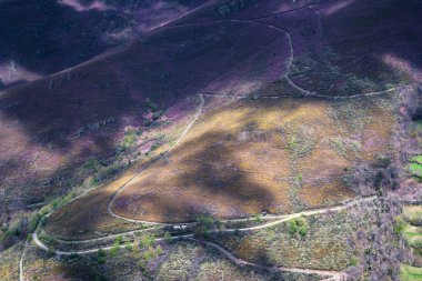 Forest tracks crisscross their curves and straights between purple heather slopes in the mountains of Courel Lugo Galicia clipart