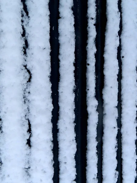 Snow on corrugated iron creating graphic background.