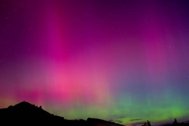 Otago, Palmerston 'daki Puketapu dağının üzerinde pembe ve yeşil Aurora Australis. Palmerston Yeni Zelanda 'nın güney ışıklarının görülebildiği Güney Adası' nda yer almaktadır.. 