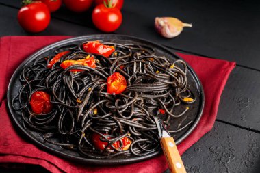 Siyah tabakta sebzeli siyah spagetti. Kara tahtada ve malzemelerde siyah makarna pişirdim. Yakın plan.