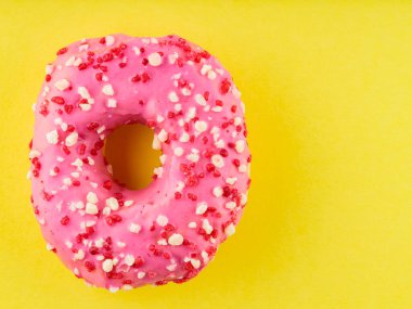 Sarı arka planda çok renkli serpiştirilmiş tatlı pembe donut. Renkli tatlı tatlı