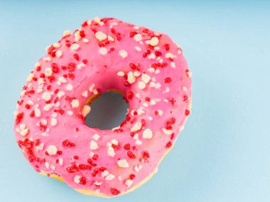 Pastel mavi arka planda kremalı çörek. Renkli malzemeli pembe donut. Boşluğu kopyala