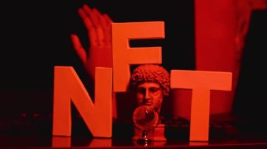 NFT yazıtları ve neon ışıklı renkli eski heykeller. İş yerinde NFT harfleri var. Kripto sanatı ve engelleme teknolojisi kavramı. Statik çekim
