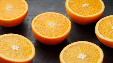 Koyu arkaplanda taze turuncu yarımlar. Meyve suyu yapmak için sulu narenciye.