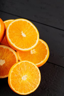 Bright halves of oranges on a wooden table. Halves of juicy oranges on black boards
