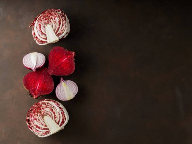 Purple vegetables on dark background. Chopped beetroot, red onion and radicchio salad for cooking. Healthy purple vegetables. Copy space