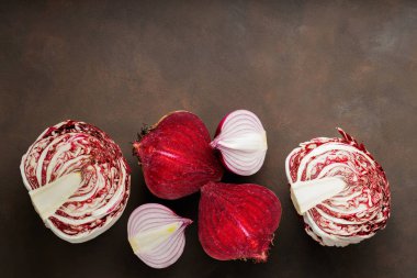 Purple vegetables on dark background. Chopped beetroot, red onion and radicchio salad for cooking. Healthy purple vegetables. Copy space