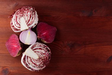 Purple vegetables on a brown wooden table. Red beetroot, red onion and radicchio salad on a wooden background. Healthy purple vegetables for cooking