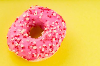 Sarı arka planda çok renkli serpiştirilmiş tatlı pembe donut. Renkli tatlı tatlı