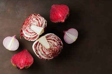 Purple vegetables on a dark background. Chopped beetroot, onion and radicchio salad for cooking. Creative still life with healthy purple vegetables. Top view