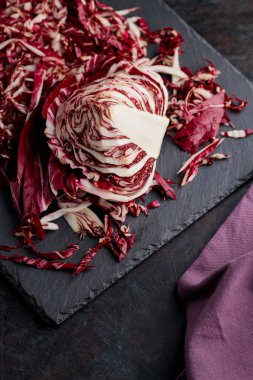 Koyu arkaplanda dilimlenmiş turşu salatası. Radichio salatası tahtada. Üst görünüm