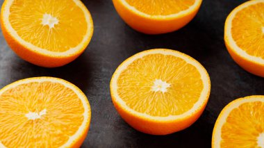 Orange slices on a black background. Halves of juicy oranges for a healthy diet