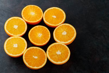 Orange slices on a black background. Halves of juicy oranges for a healthy diet