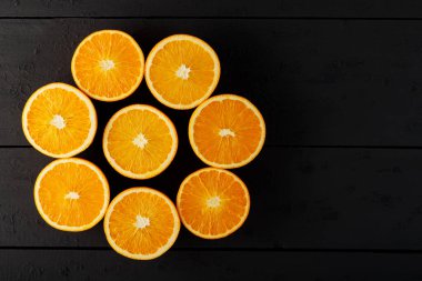 Bright halves of oranges on a wooden table. Halves of juicy oranges on black boards