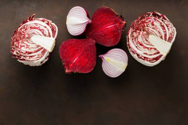 Purple vegetables on dark background. Chopped beetroot, red onion and radicchio salad for cooking. Healthy purple vegetables. Copy space