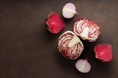 Purple vegetables on dark background. Chopped beetroot, red onion and radicchio salad for cooking. Healthy purple vegetables. Copy space