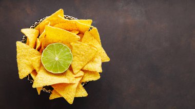 Mexican nacho chips and lime on a dark background. Traditional mexican food. Copy space