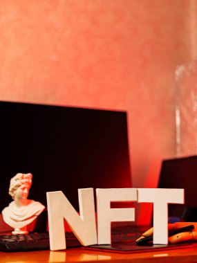 NFT inscription and artificial hand at the designer's workplace. Non-Fungible token lettering in neon light. Futuristic cryptocurrency concept